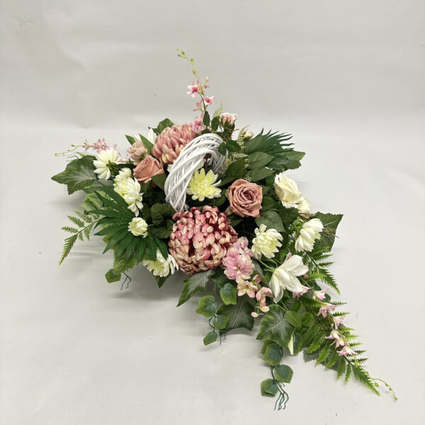 Biało-różowa kompozycja z białym wiklinowym wiankiem, wykonana z różowych i białych chryzantem, róż i clematisy